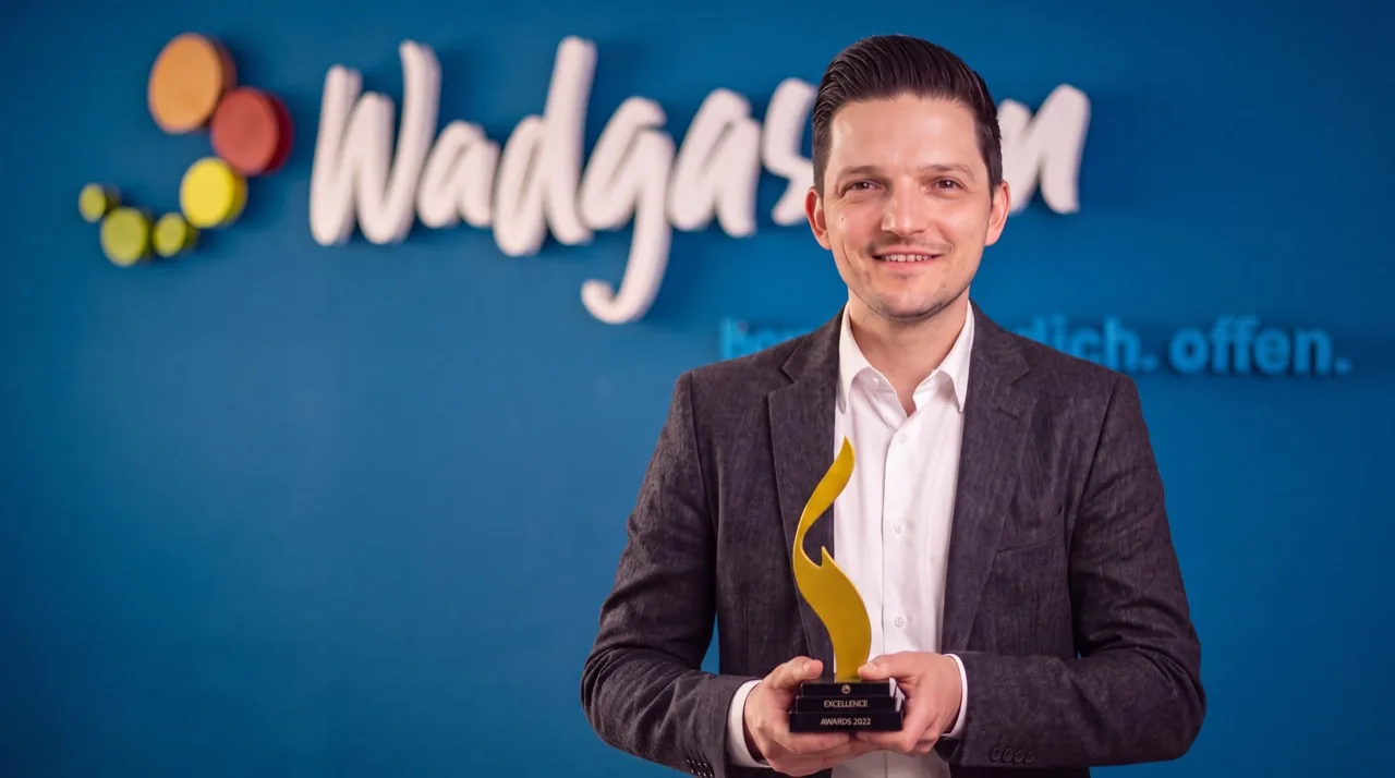 Sebastian Greiber hält den HR Excellence Award 2022 vor dem Wadgassen-Schriftzug